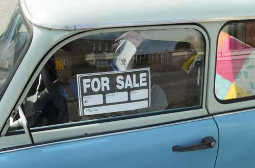 A car has a 'for sale' sign in the window